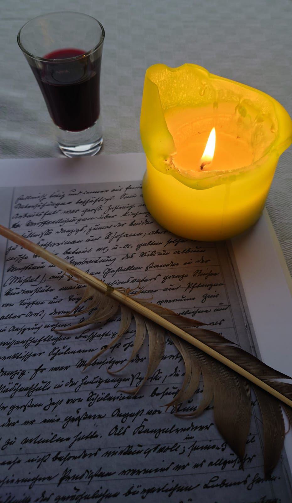 Bild mit Weinglas, Kerze, Blatt Papier und einem Federkiel